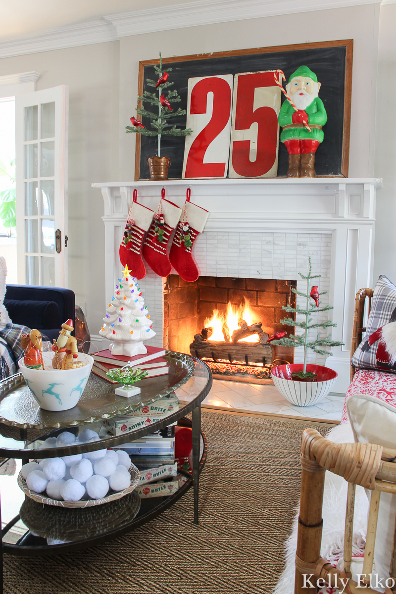 Love this vintage Christmas mantel with elf blow mold and big metal 25 numbers kellyelko.com #christmas #christmasdecor #christmasdecorations #christmasdecoratingideas #christmasmantel #vintagechristmas #retrochristmas #farmhousechristmas #christmasfireplace #christmaslivingroom #cozychristmas #holidayhousewalk #christmastrees #sparsechristmastree #feathertree #blowmold #christmasblowmold 