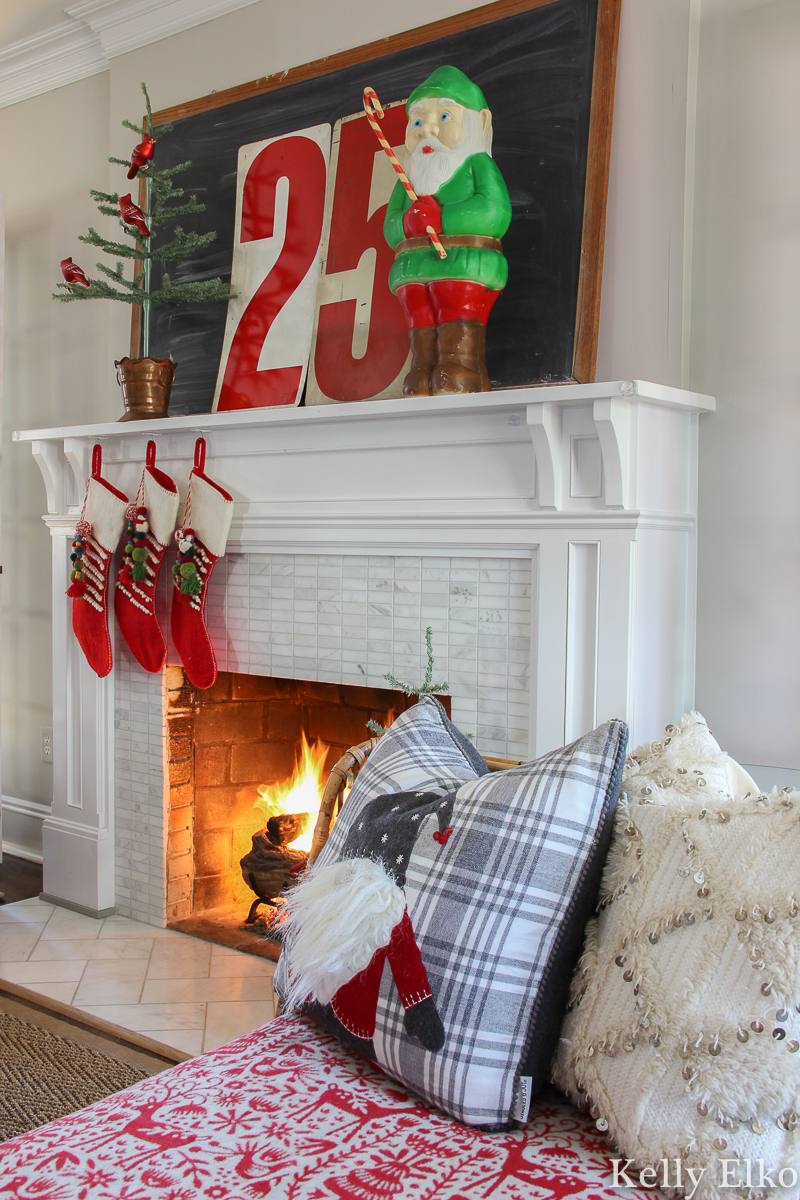 Love this retro Christmas mantel with elf blow mold and huge 25 numbers kellyelko.com #christmas #christmasdecor #christmasdecorations #retrochristmas #vintagechristmas #christmasmantel #christmasfireplace #farmhousechristmas #colorfulchristmas #christmasstockings #feathertree #gnome