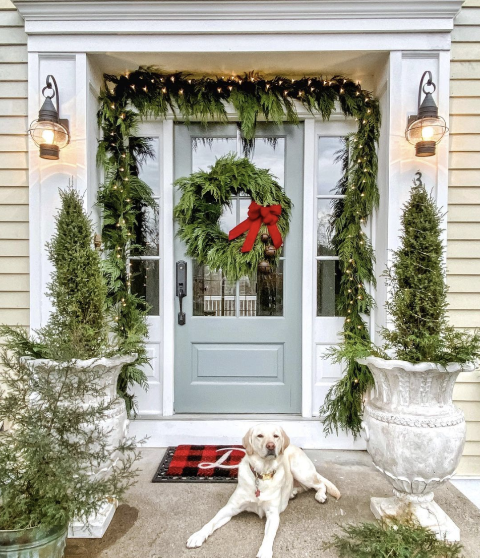 Favorite festive Christmas porches - love this classic fresh garland and wreath with big red bow #christmas #christmasporch #outdoorchristmasdecor #christmaswreath #christmasgarland #classicchristmas #farmhousechristmas 