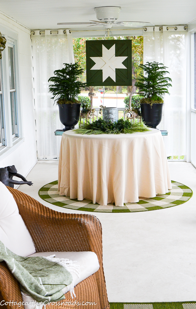 Love this Christmas porch with tabletop trees and a wood sign that looks like an old barn quilt #christmasporch #christmasdecor #diychristmas #diychristmasdecor #farmhousechristmas #christmastrees #tabletoptree