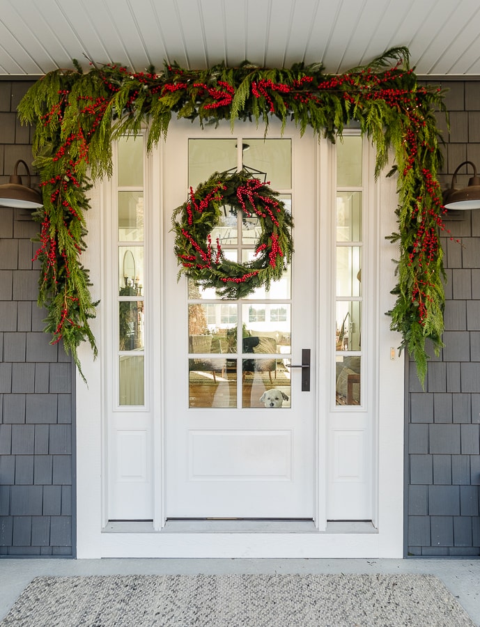 Love the red berry garland and wreath on this classic Christmas porch #christmas #christmasporch #christmasgarland #christmaswreath #diychristmas #farmhousechristmas 