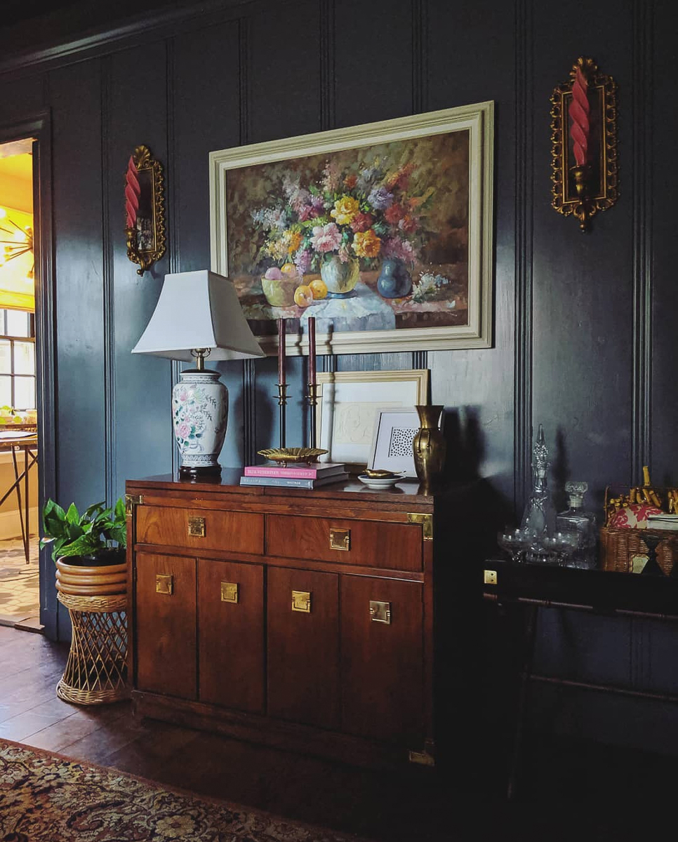 Dramatic dining room with dark painted walls and vintage rolling server