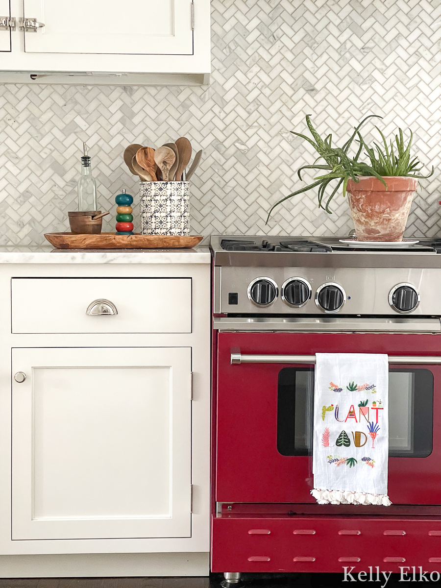 Beautiful red stove in a white kitchen with herringbone marble backsplash kellyelko.com