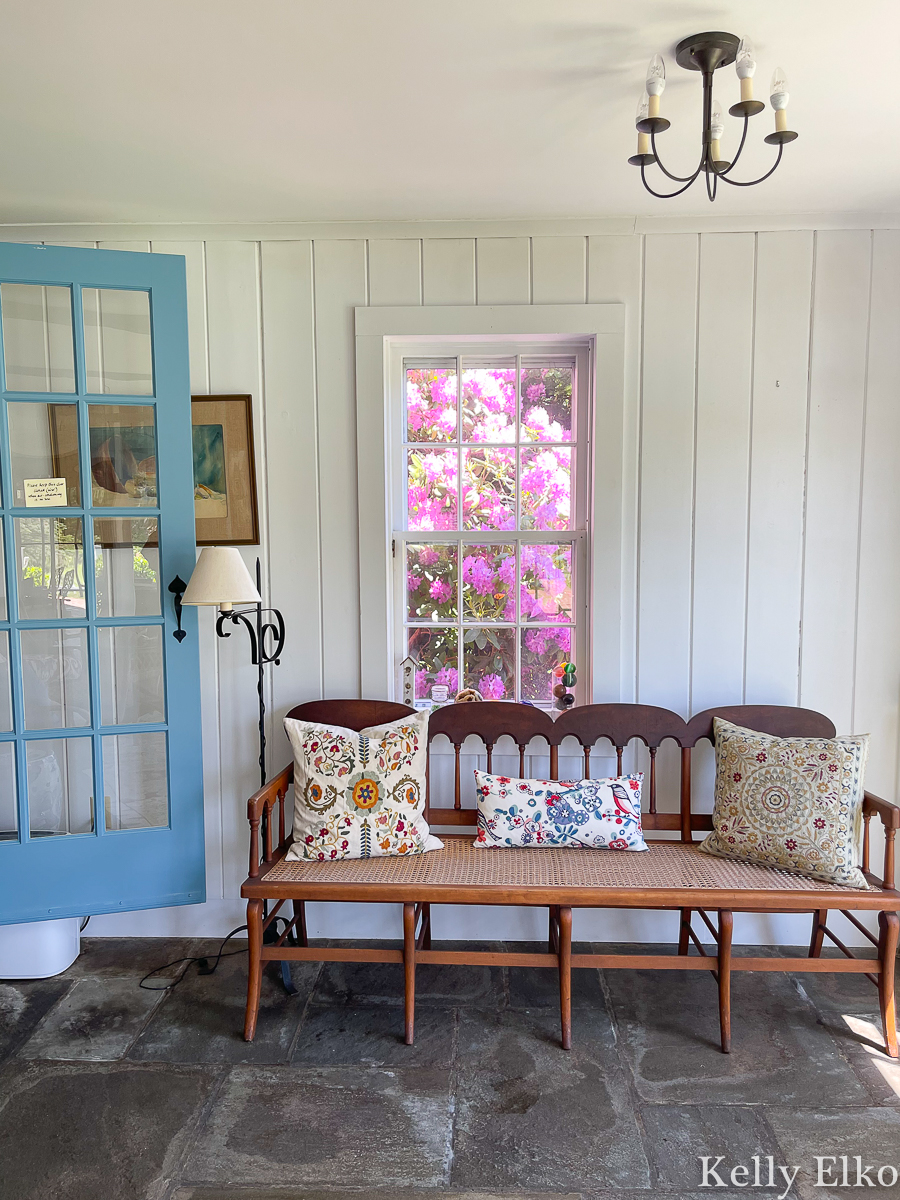 Lovely sunroom with stone floor and cane bench kellyelko.com