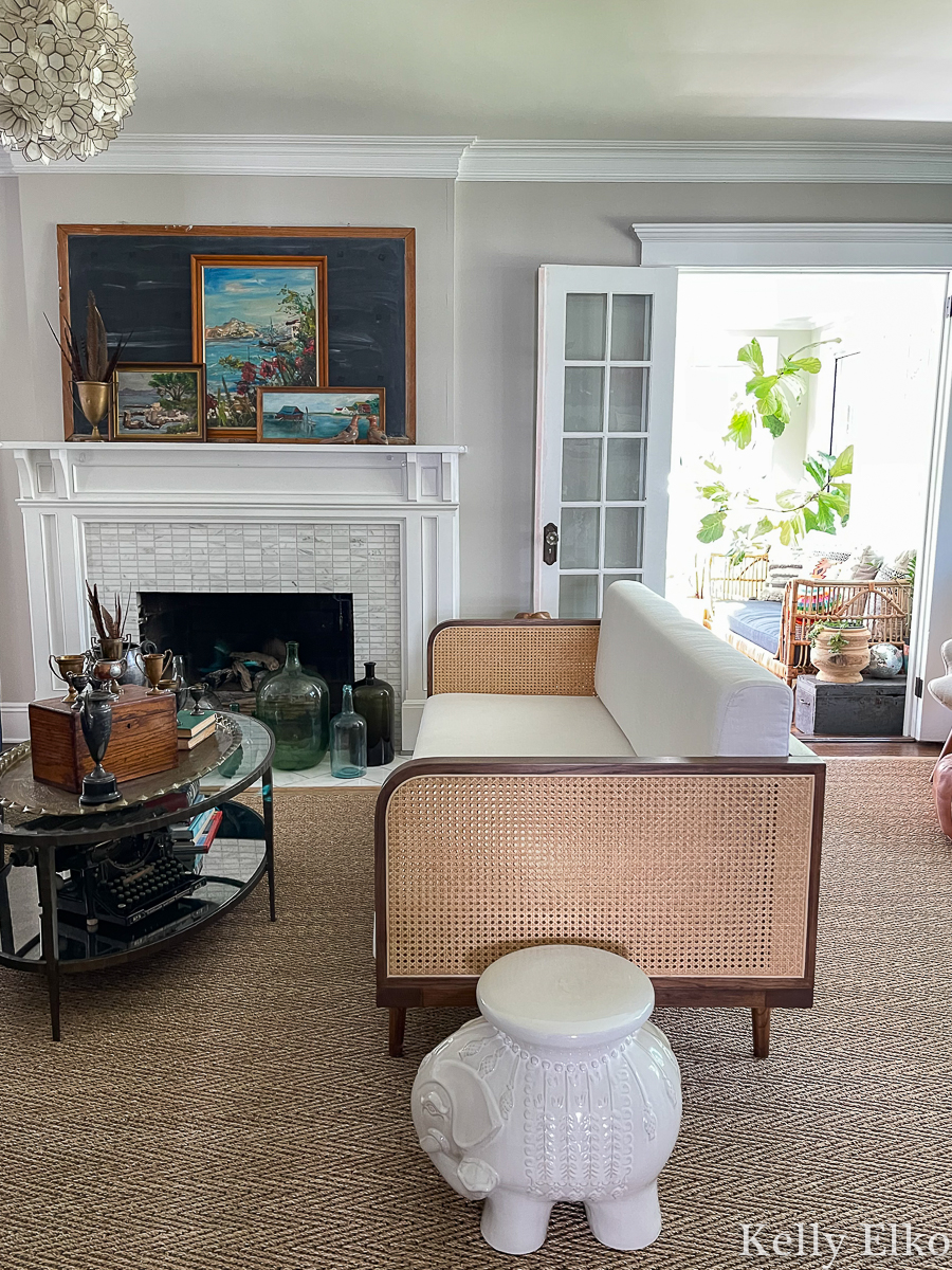 Eclectic living room tour - love the vintage art on the mantel and the cane sofa kellyelko.com