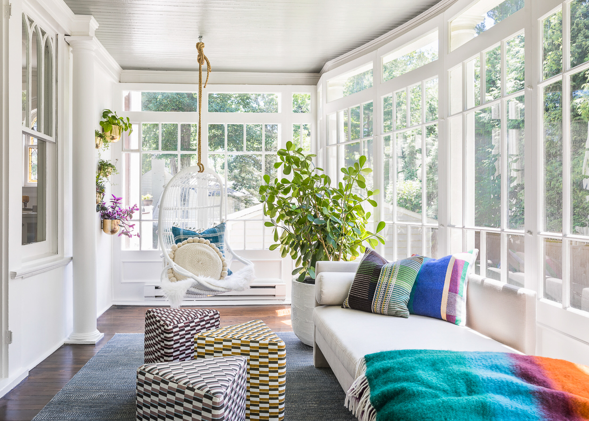 White sunroom with hanging egg chair and colorful plants kellyelko.com