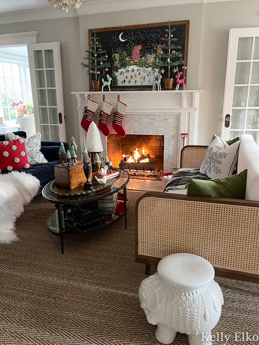 Christmas Home Tour - love this stunning colorful Christmas mantel with sparse trees, colorful art and red pom pom stockings kellyelko.com