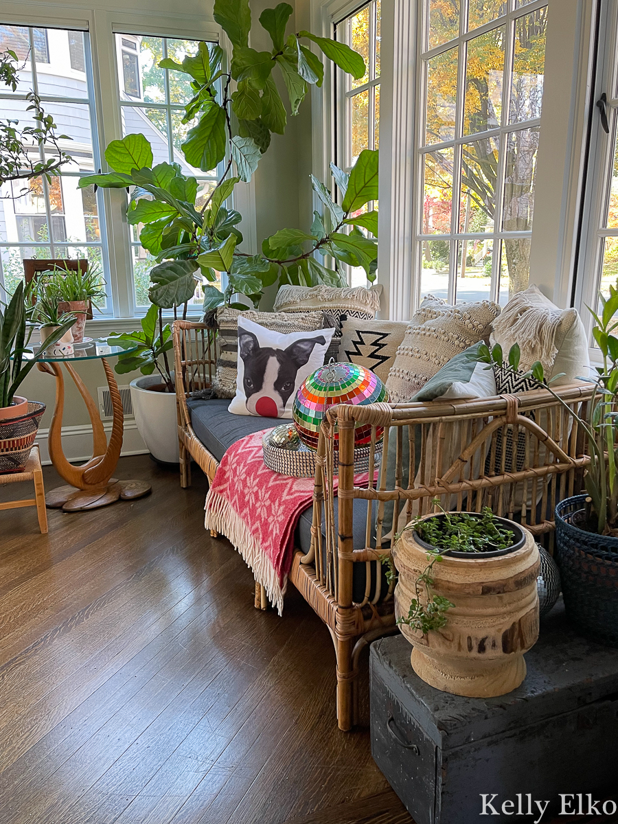 Love this festive sunroom for Christmas - the rattan daybed with red throw and reindeer pillow kellyelko.com