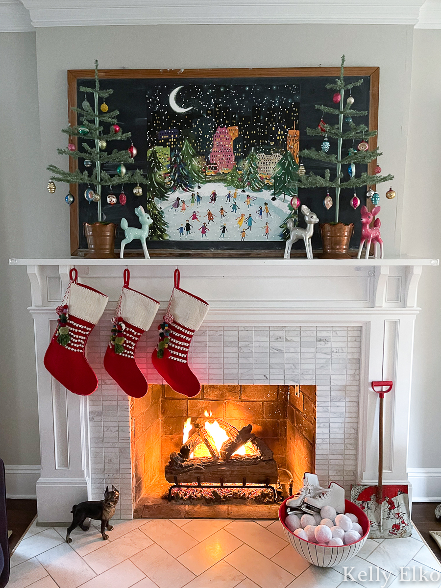 Love this whimsical and colorful Christmas mantel with cute ice skater art and feather trees dripping in vintage Shiny Brite ornaments kellyelko.com