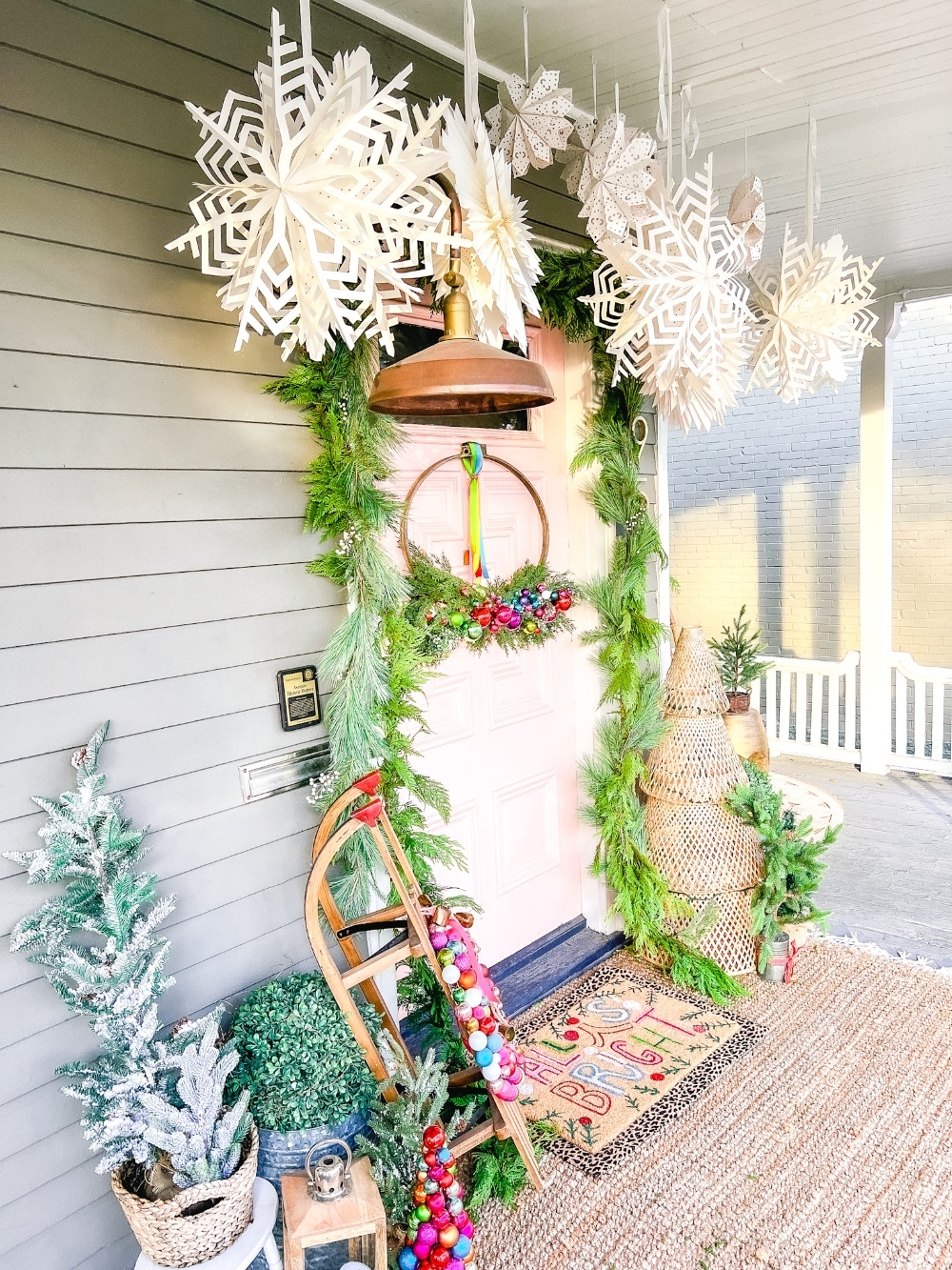 Colorful Christmas porch - love the giant paper snowflakes and pink front door 