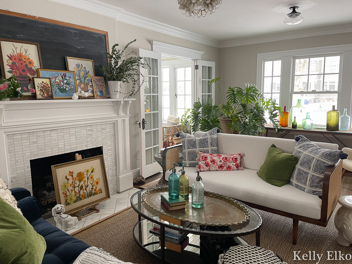Eclectic living room with vintage art, cane sofa, and huge philodendron