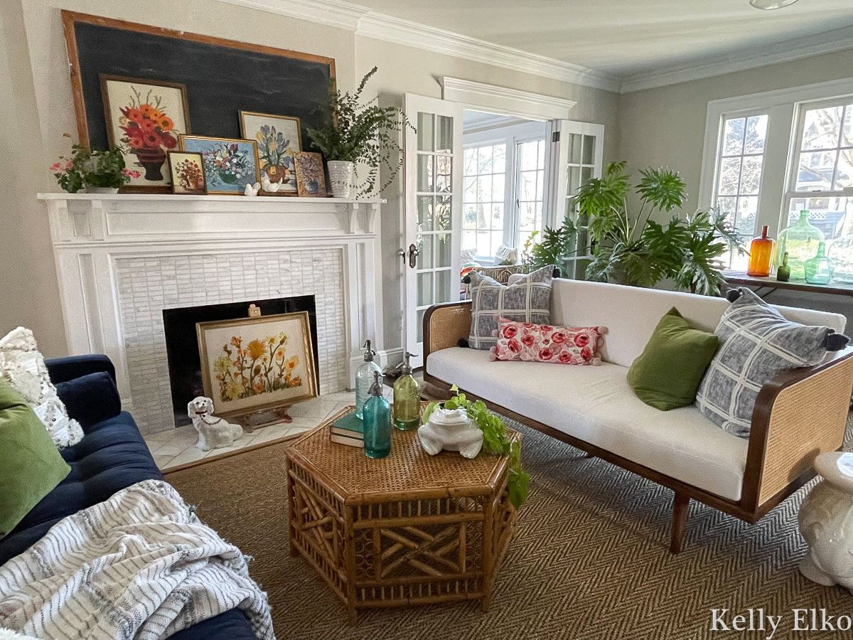 Boho eclectic living room with vintage floral art and rattan and cane furniture and huge houseplants kellyelko.com