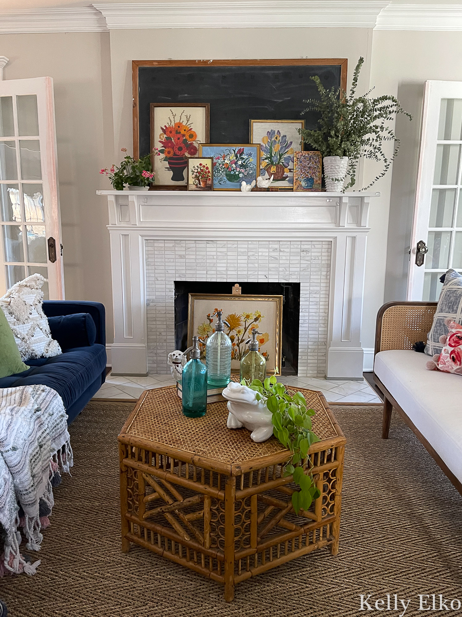 Boho living room with a collection of vintage floral art and the coolest rattan and cane coffee table kellyelko.com