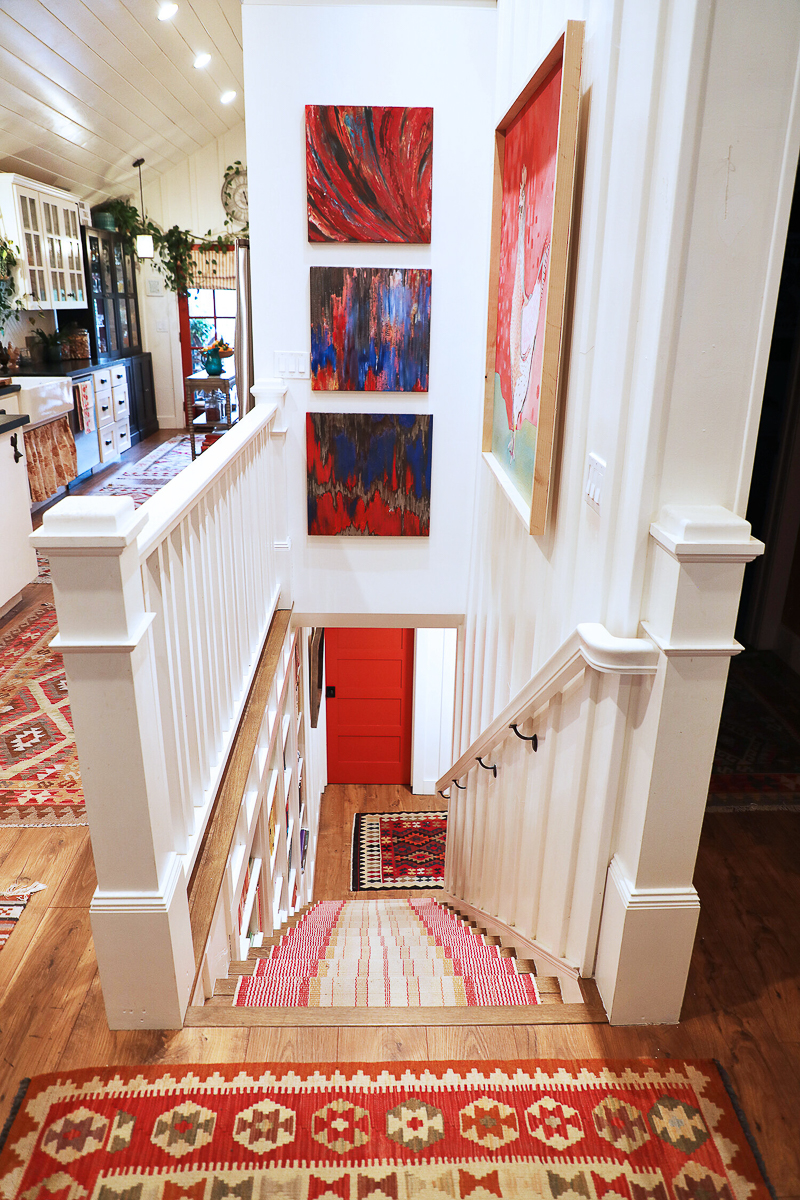 Basement stairs with beautiful banister and colorful runner 