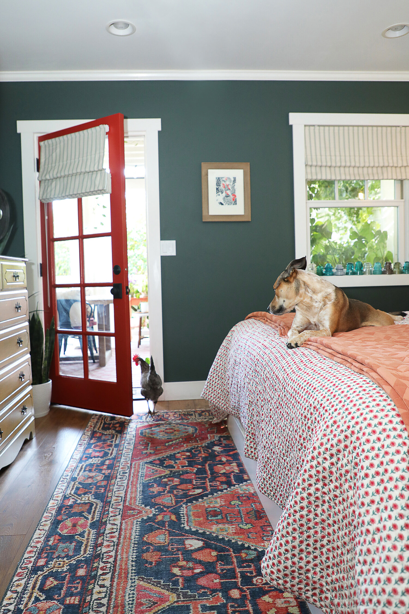 Bedroom with dark green walls and red door 