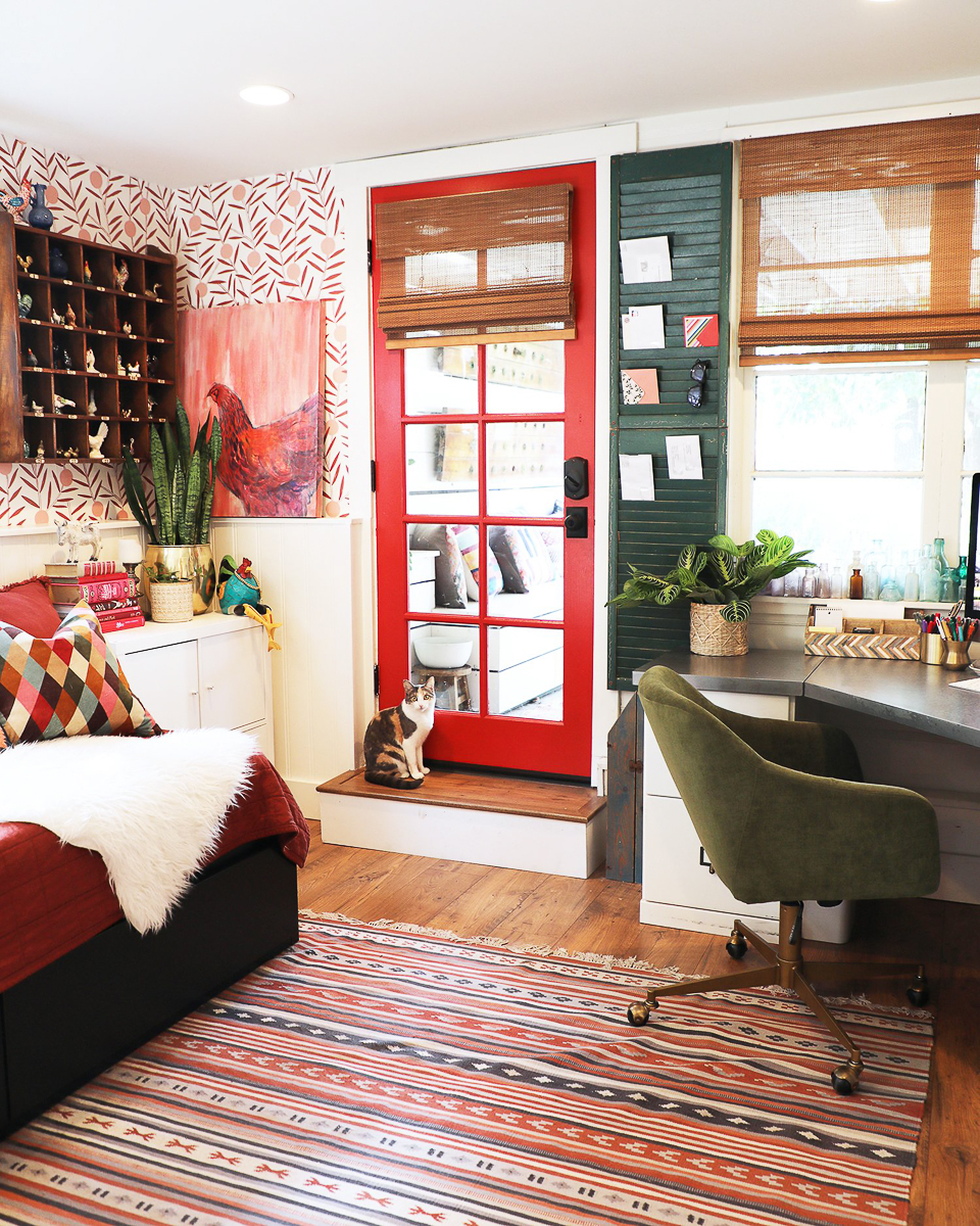 Home office guest room with whimsical wallpaper and red door 