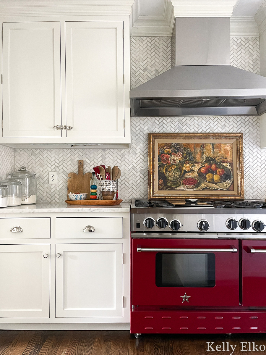 Love the still life painting above the red stove in this white farmhouse kitchen kellyelko.com