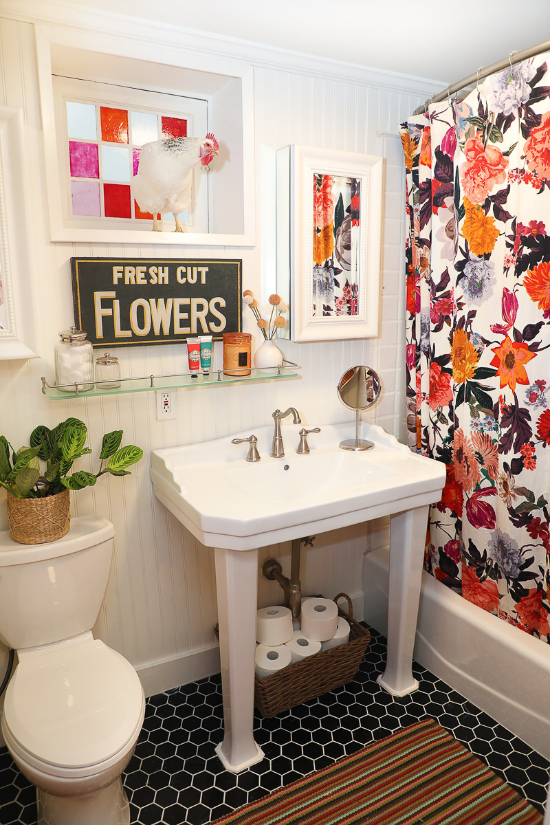 Black and white bathroom with colorful shower curtain and stained glass window 