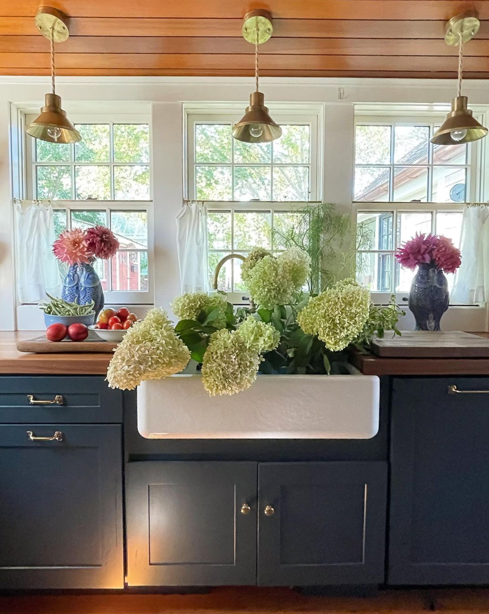 Coastal kitchen with blue cabinets, farmhouse sink and brass scones 