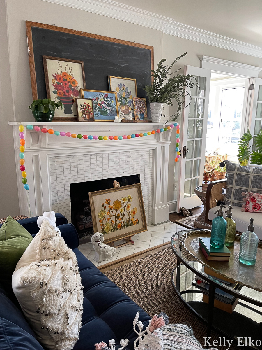 Love this colorful mantel with vintage floral art and DIY egg garland for spring kellyelko.com