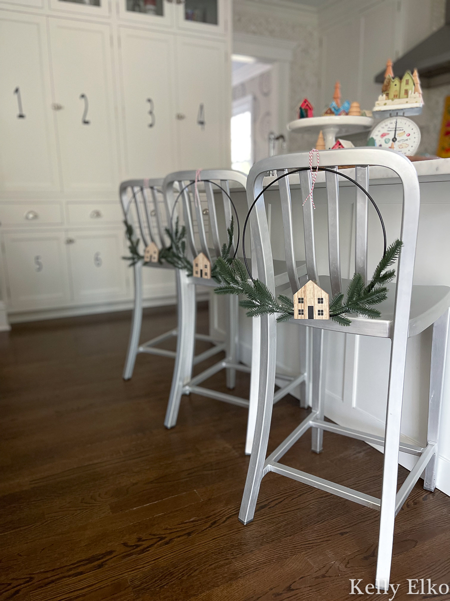 Cute little wire wreaths with little wood houses tied to back of chairs in this white kitchen kellyelko.com