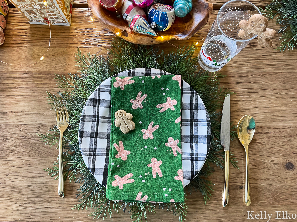 Love the layered look of a cedar placemat, plaid plate and adorable gingerbread man napkin on this festive Christmas table kellyelko.com