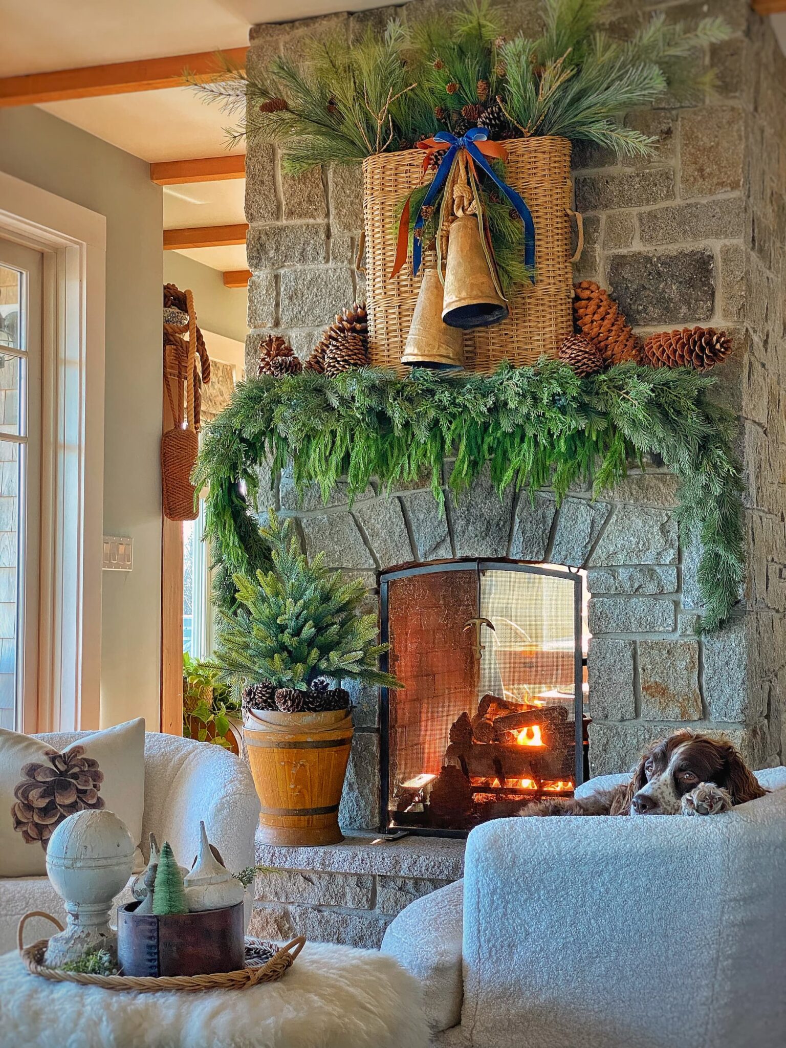 Gorgeous Christmas mantel with natural greenery garland, pinecones, basket and brass bells