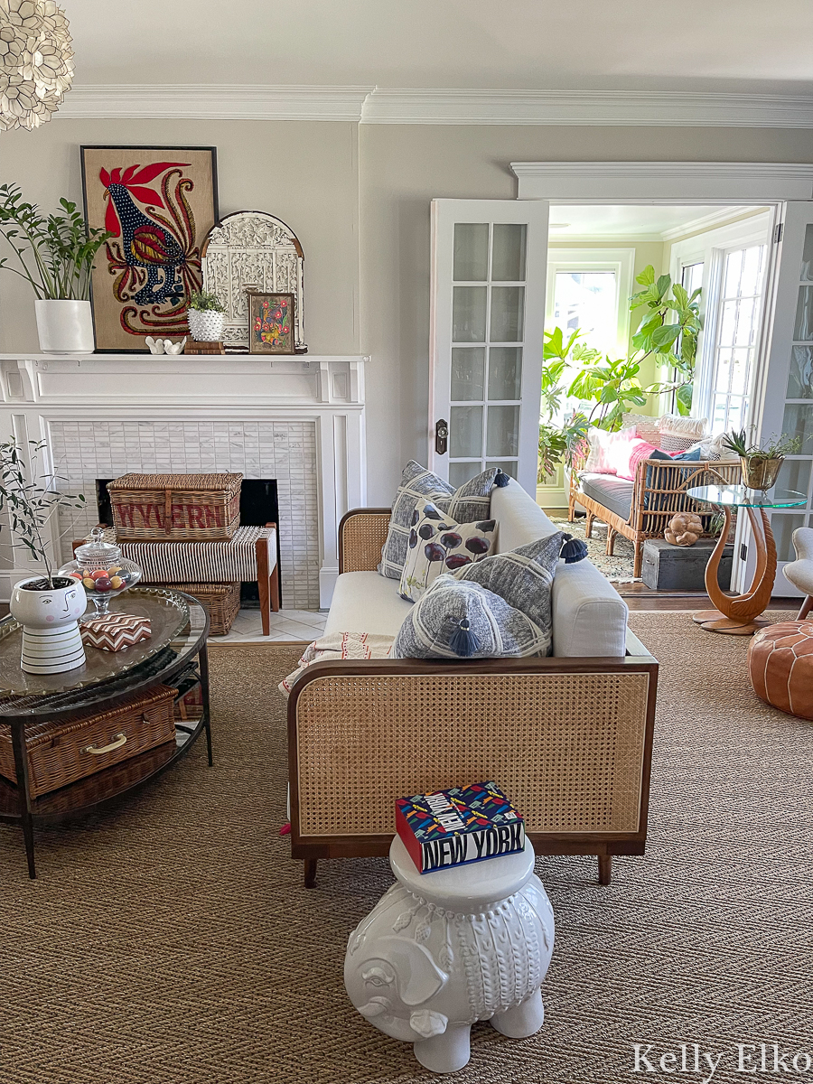 Stunning eclectic living room with a bohemian feel from cane and wicker, vintage art, colorful accessories and lots of plants kellyelko.com