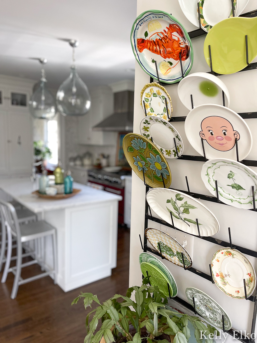 What a fun, colorful, eclectic and whimsical plate wall on a mug rack in this farmhouse kitchen kellyelko.com
