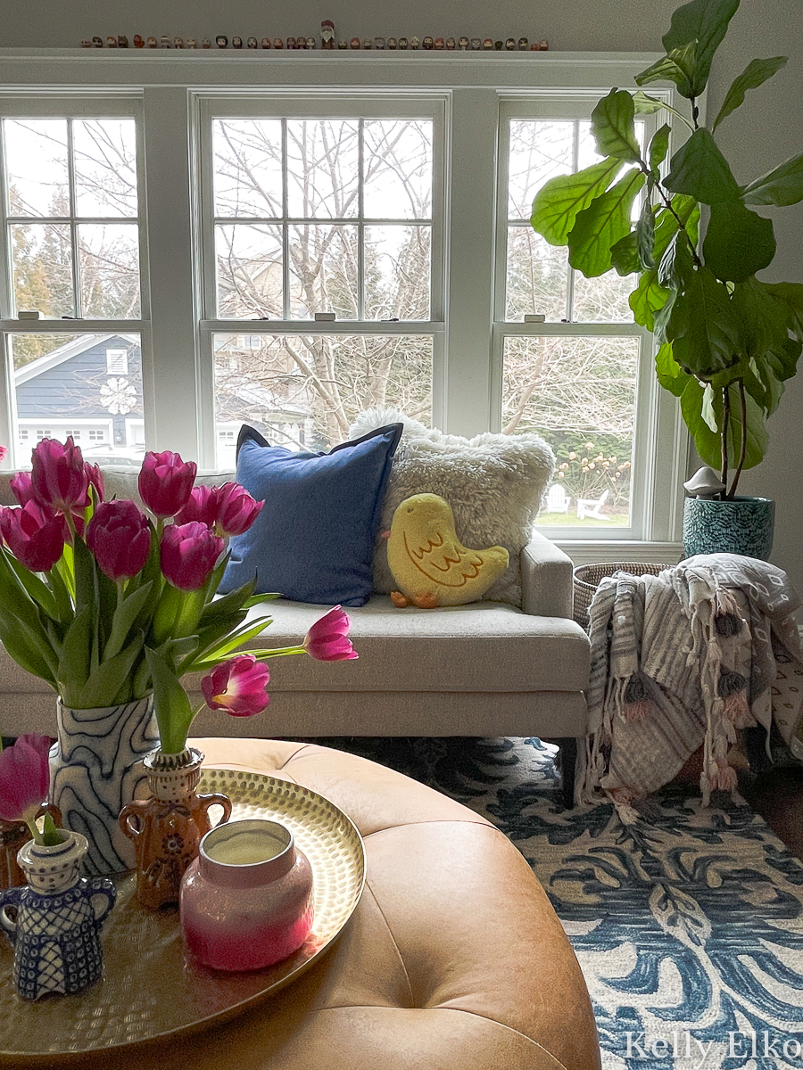 Cozy family room with leather ottoman, fiddle leaf fig, pink tulips, Polish pottery and a cute little yellow chick pillow kellyelko.com