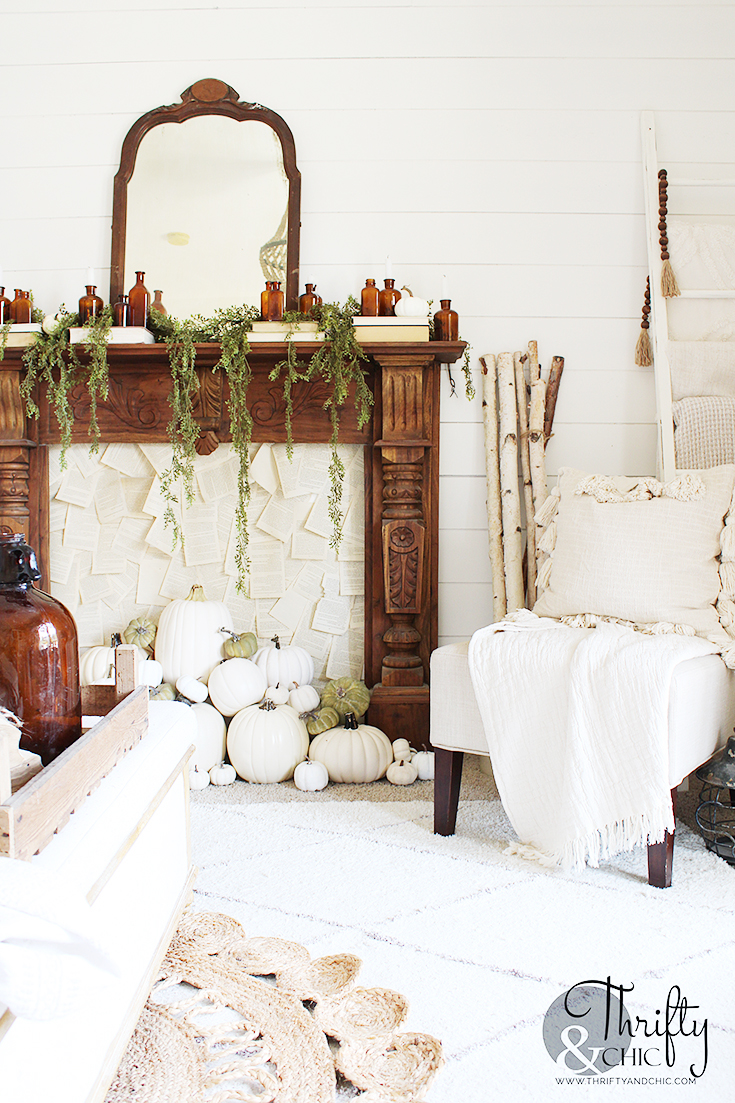 Beautiful carved wood mantel with antique amber bottles and old books and white pumpkins in the fireplace / kellyelko.com